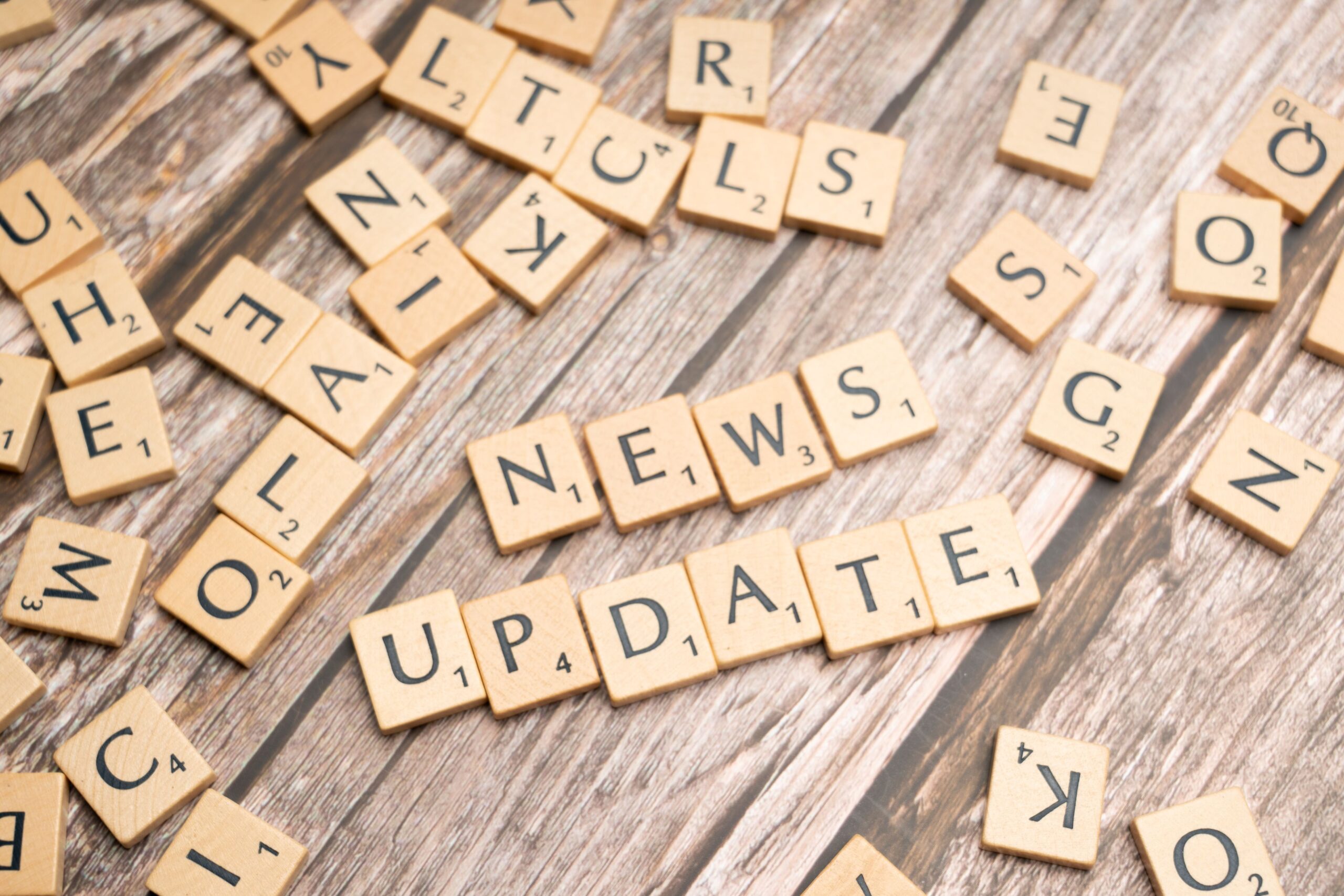 Newsletter Scrabble tiles spelling 'News Update' on a wooden background, ideal for media and communication concepts.