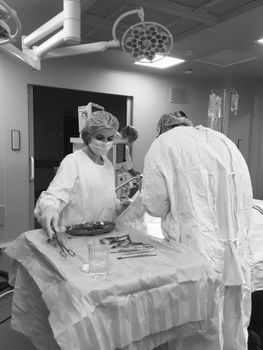 Black and white image of surgeons working in an operating room, focused on healthcare and medical procedures.