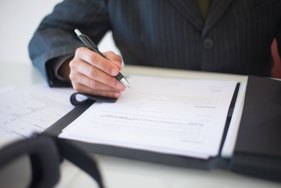 FSATA Designation Close-up of a hand signing documents with a pen, symbolizing an important business contract.